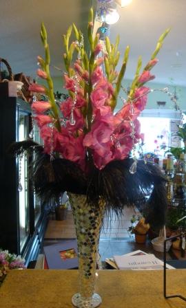 Tall mirrored vase with black feathers pink gladiolas and hanging crystals