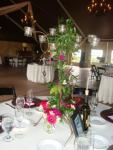 Greenery with a few flowers wrapped around Keyways candelabras. 3 small vases around the bottom with flowers for the guest to take home.