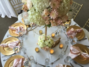 Gold candelabras with crystals draping. With an arrangement of white hydrangea, blush roses, peach stock, blush cushions and blush alstilbe.